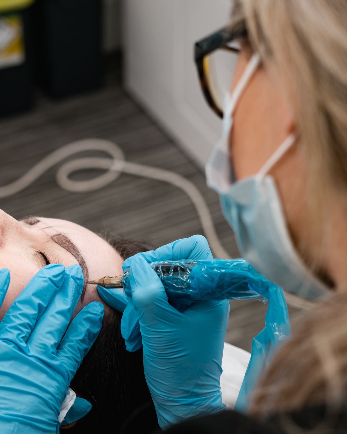 Mary Spence placing hair strokes on a client's brow with a digital machine